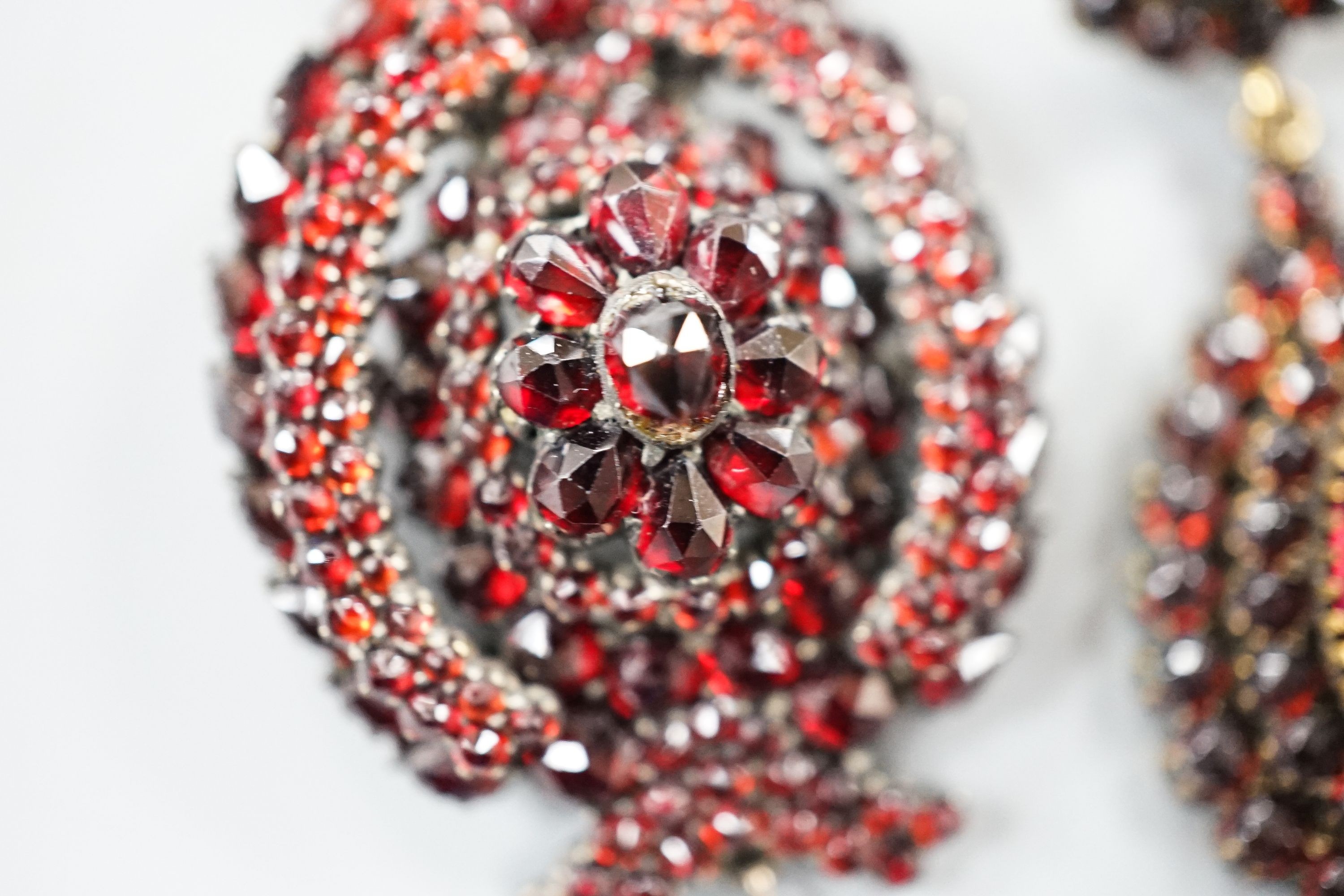 A pair of Victorian gilt metal and facet cut garnet set drop earrings, 51mm and a similar white metal and garnet set pendant brooch.